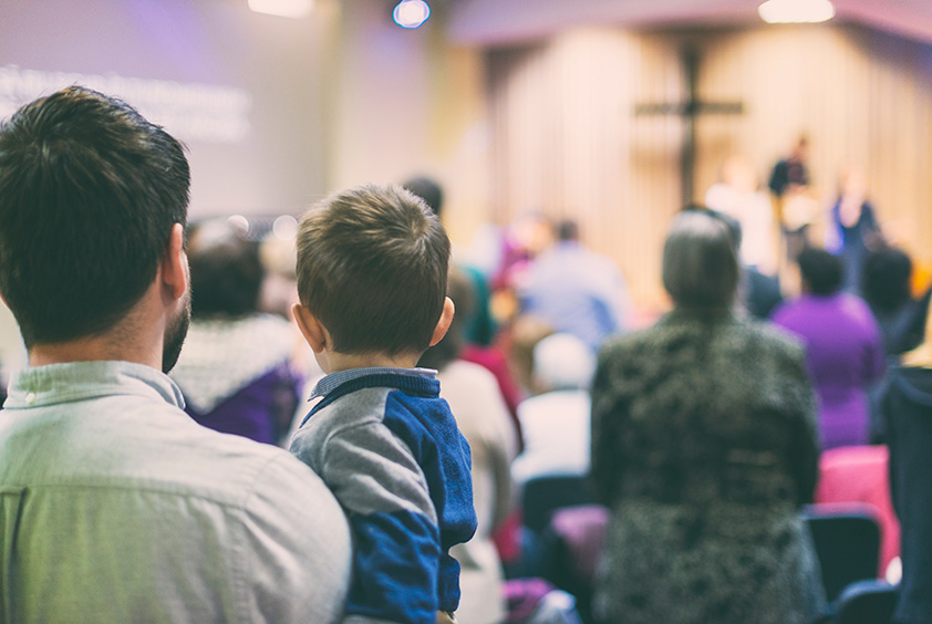 Father with his son participate at christian congregation worship